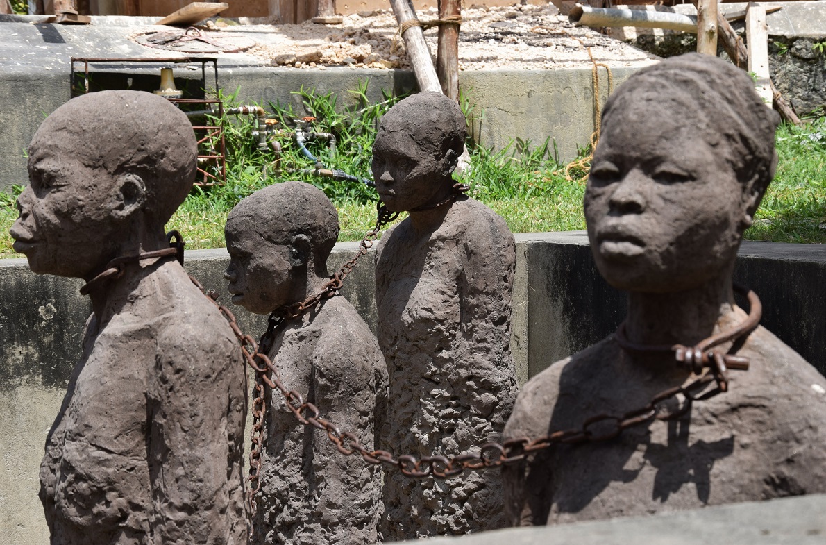 Old Slave Market, Stone Town, Zanzibar, Tanzania.   Μνημείο αφιερωμένο στους σκλάβους που πέρασαν από την «αγορά» μέχρι την απαγόρευση της δουλείας . Οι αλυσίδες του μνημείου είναι αληθινές, ενώ  οι ιστορίες και οι εικόνες από τα στοιβαγμένα, υπερπλήρη και μικροσκοπικά υπόγεια που κρατούνταν οι υπό πώληση άνθρωποι, προκαλούν το λιγότερο ανατριχίλα και φρίκη.