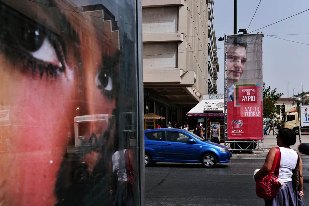 People walk past a pre-election poster of the leader of the Greece's radical-left Syriza party, Alexis Tsipras, in central Athens on September 7, 2015, ahead of upcoming snap parliamentary elections on September 20. An opinion poll suggests that Greece's former governing radical left party has dropped marginally behind the main opposition conservatives in popularity, for the first time since it gained power in January 2015. AFP PHOTO/ LOUISA GOULIAMAKI
