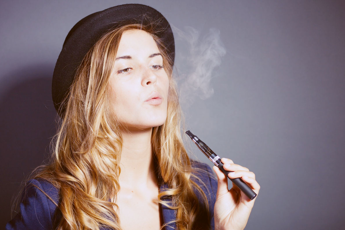Elegant woman smoking e-cigarette with smoke wearing suit